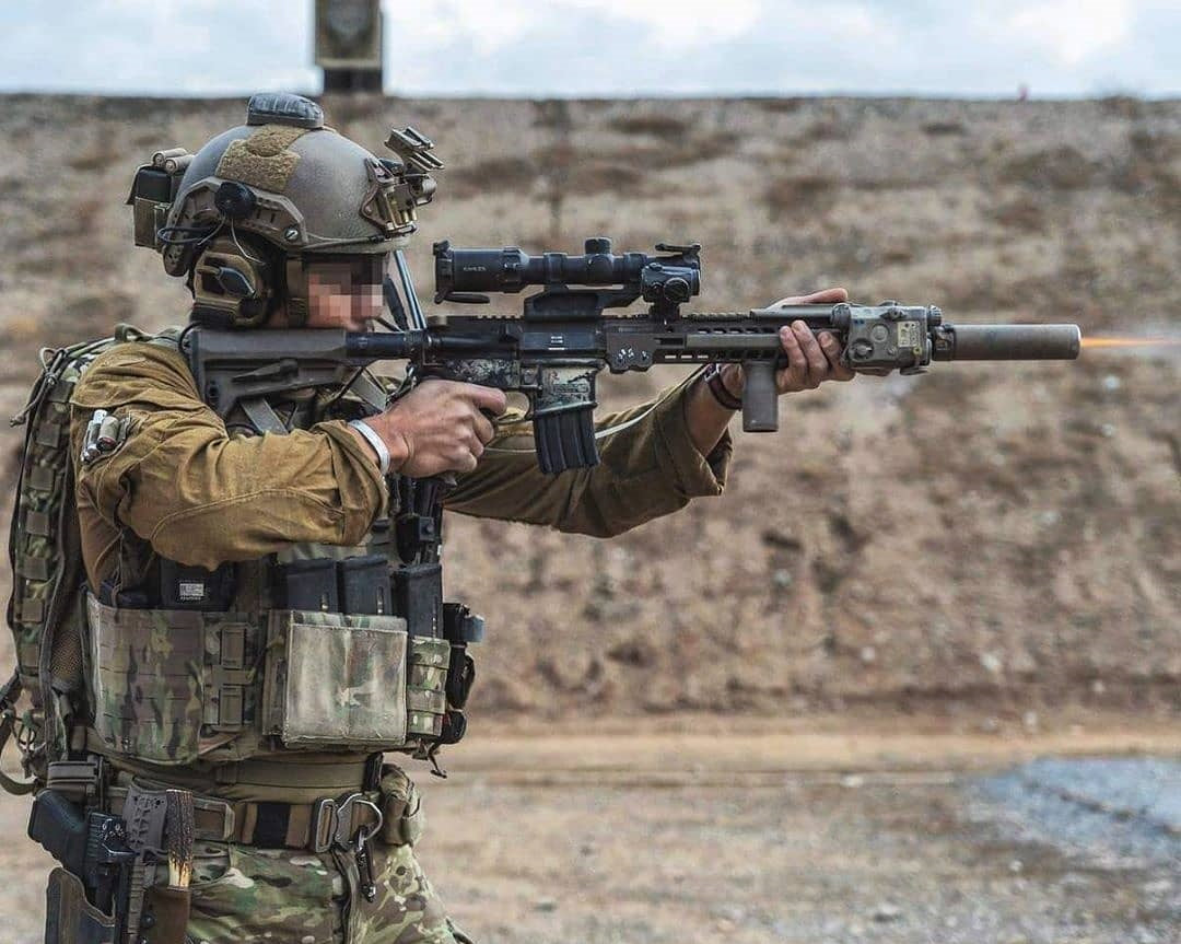 Person wearing a helmet, plate carrier and magazine pouches at a shooting range