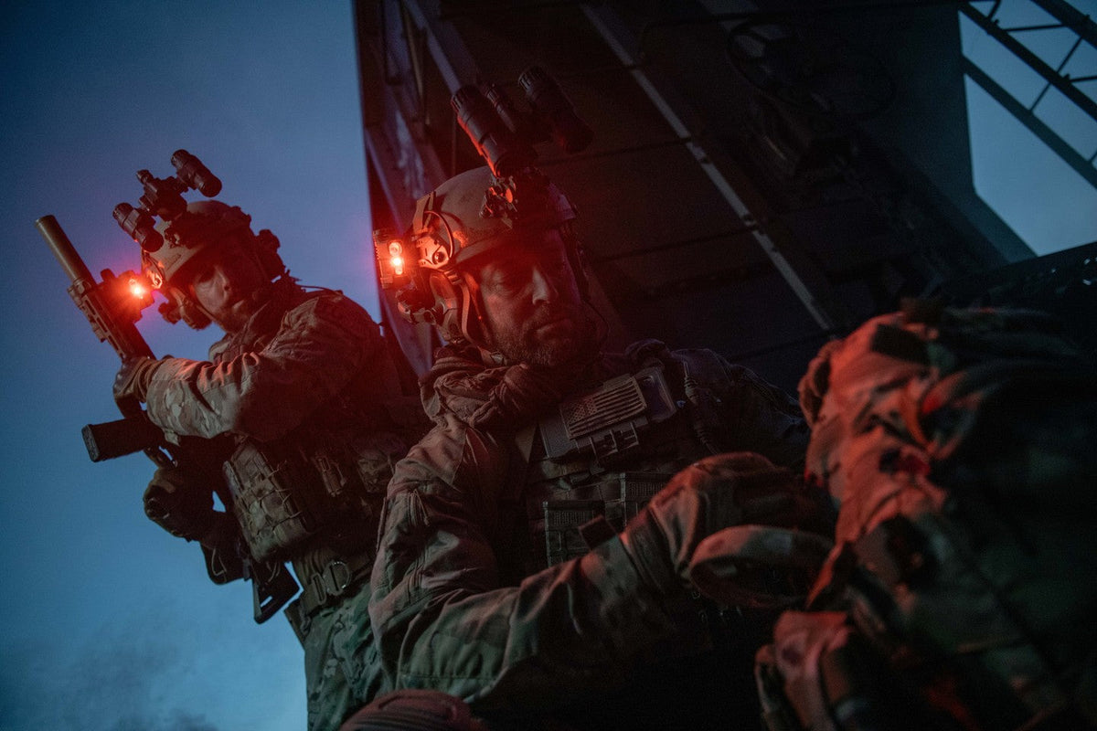 Two helmeted operators at night with red Princeton Tec task lights illuminated.